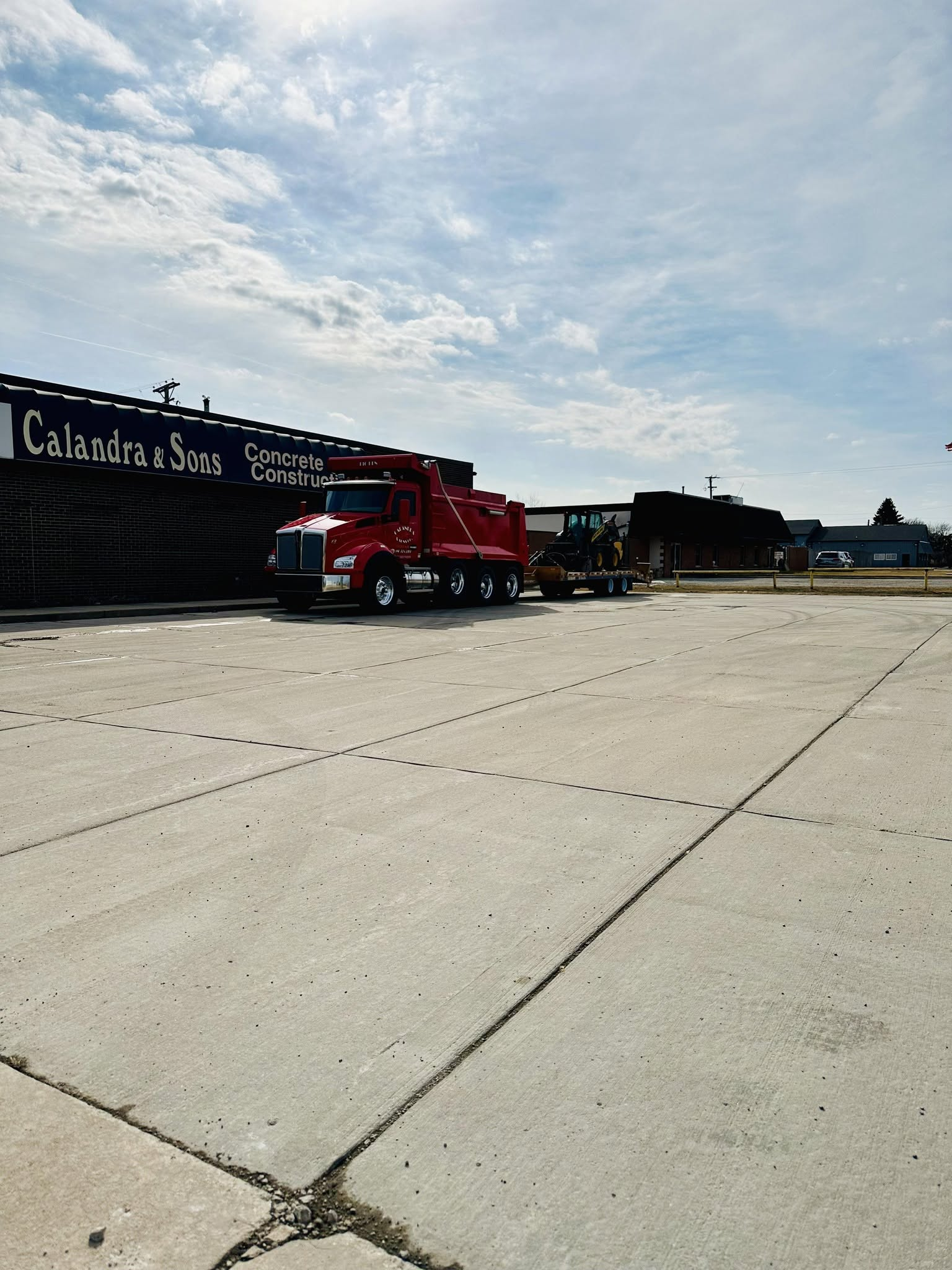 Calandra & Sons red dump truck and equipment outside the concrete construction shop